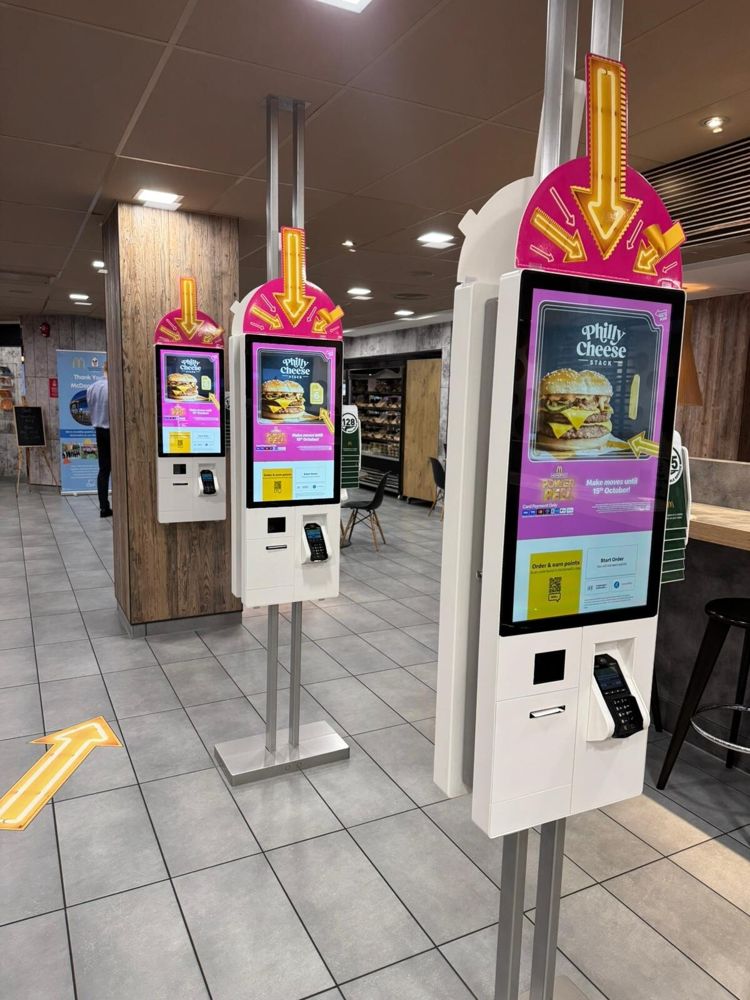 Row of MGtal self-order kiosks with card payment terminals in a restaurant