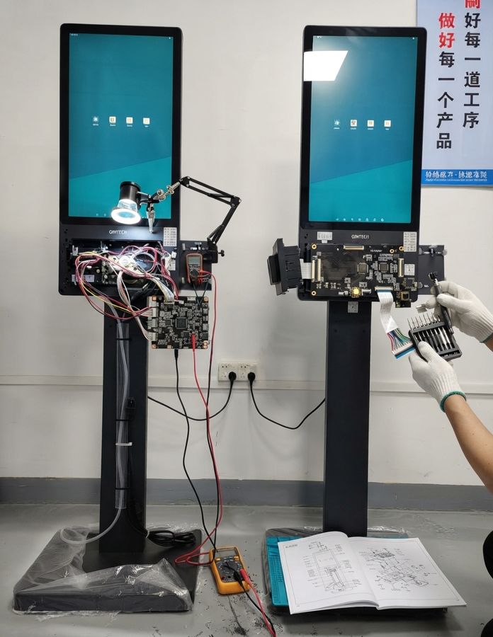 Technician testing the electronics of two kiosk prototypes